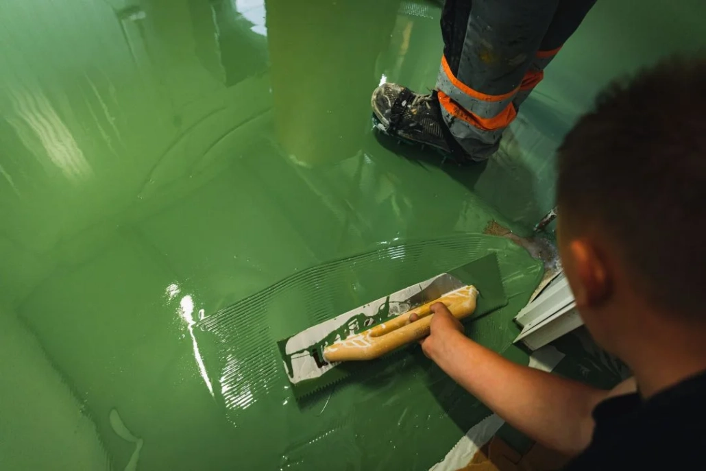 Aksaray epoksi zemin kaplama uygulaması sırasında ustanın yeşil epoksi zemini mala ile yayması
