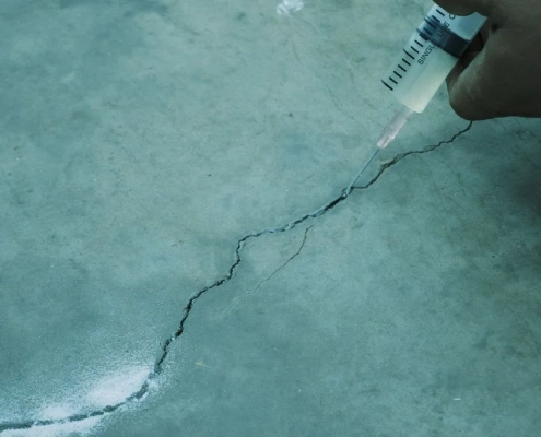 Beton yüzeydeki çatlakların epoksi enjeksiyon yöntemiyle doldurularak su sızdırma probleminin giderilmesini gösteren yakın çekim uygulama görüntüsü.